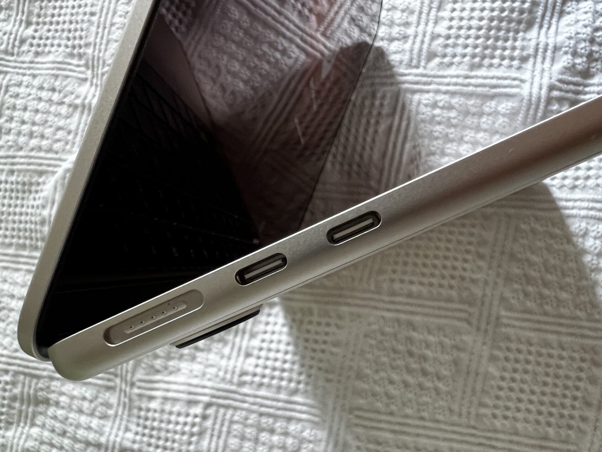 Das MacBook Air in Polarstern von der Seite gesehen. 2 USB-C-Anschlüsse und der MagSafe-Anschluss zum Aufladen